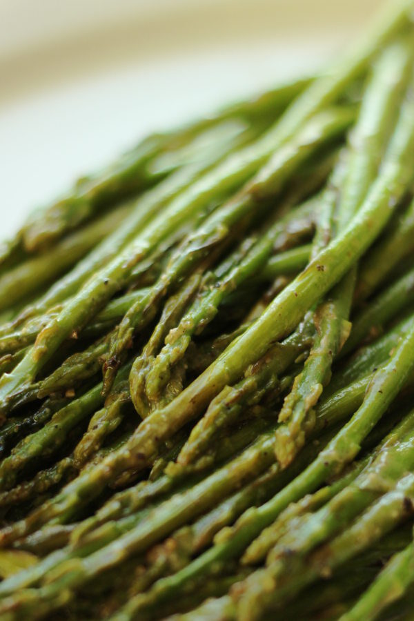 Asparagus that has been roasted in miso paste is lying on a white platter ready to serve for dinner.