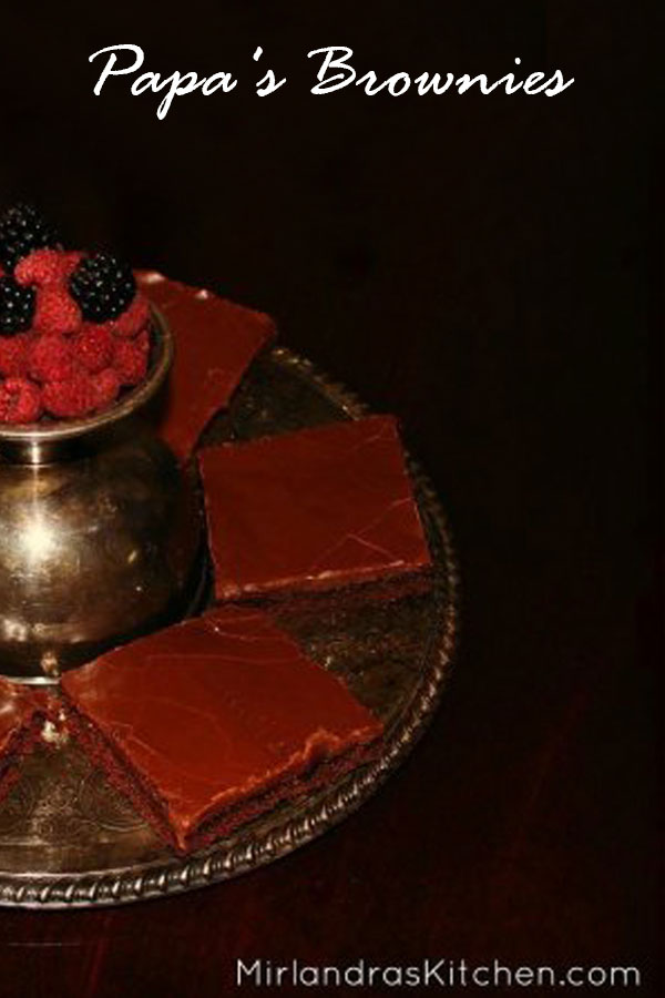 A antique silver plate is loaded up with slices of Texas sheet cake. In the center a silver goblet holds raspberries and blackberries.