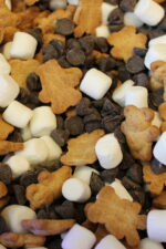 This is a close up image of smores snacke mix. You can see teddy grahams, mini marshmallows and chocolate chips all mixed together waiting to be munched on.