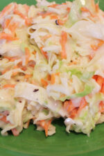 This sweet and tangy coleslaw is heaped up on a green plate ready to eat.