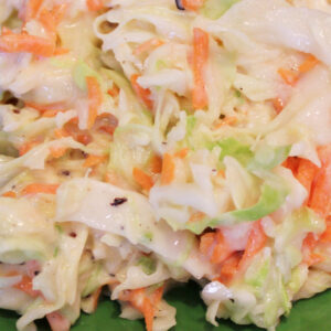 This sweet and tangy coleslaw is heaped up on a green plate ready to eat.