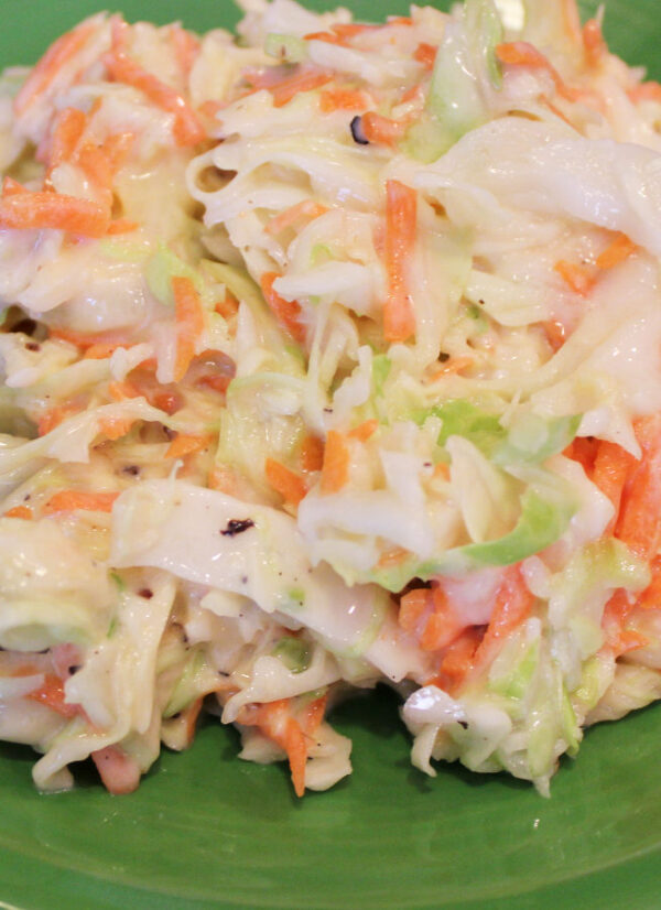 This sweet and tangy coleslaw is heaped up on a green plate ready to eat.