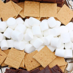 An elegant silver tray holds marshmallows, graham crackers, and large slices of fudge ready to be assembled into smores.
