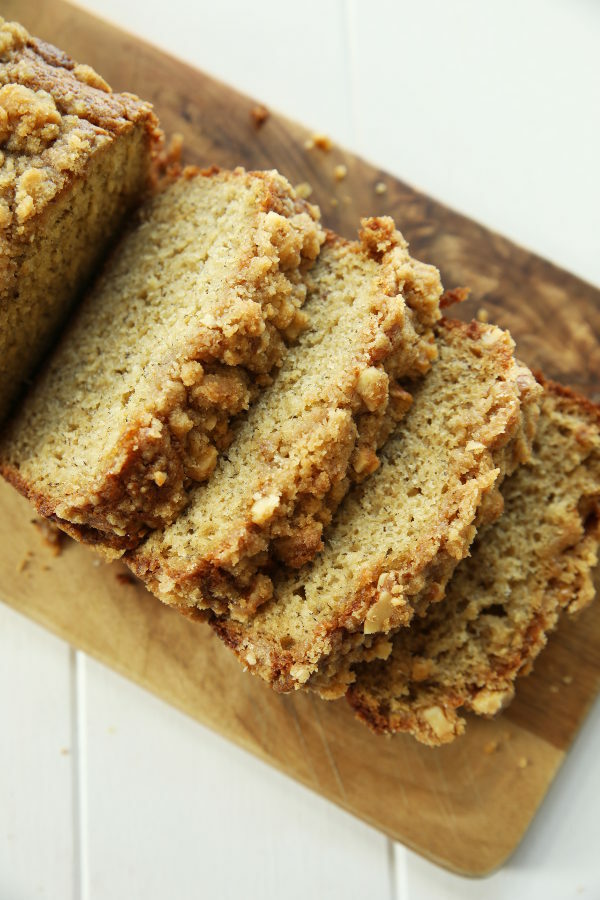 Slices of banana bread sit on a wooden cutting board ready to be eaten. 