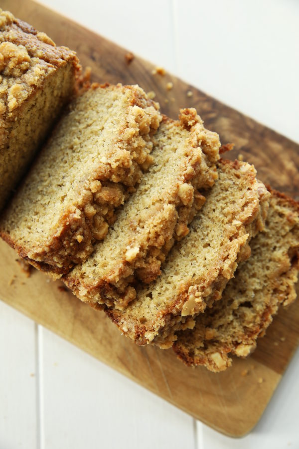 Slices of banana bread sit on a wooden cutting board ready to be eaten.