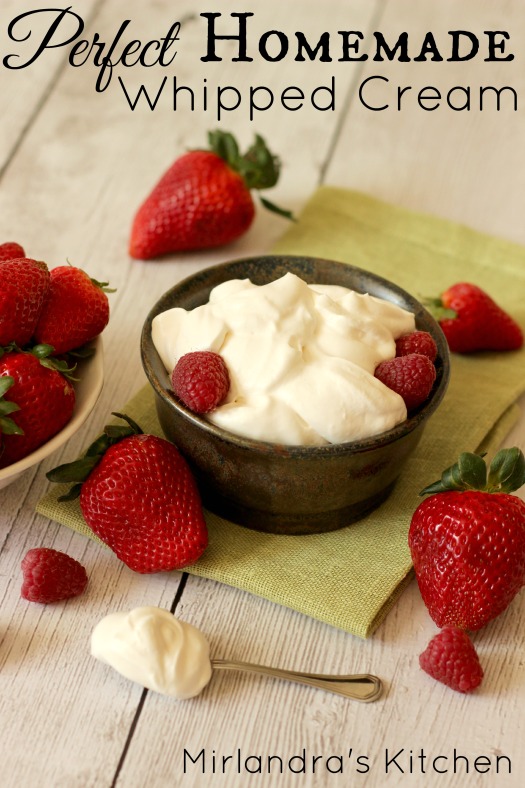 A pottery bowl of whipped cream garnished with strawberries and raspberries.