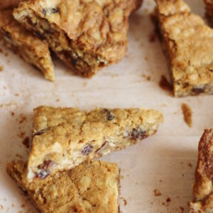 Oatmeal raisin cookie bars are cut into triangles and scattered on parchment paper.