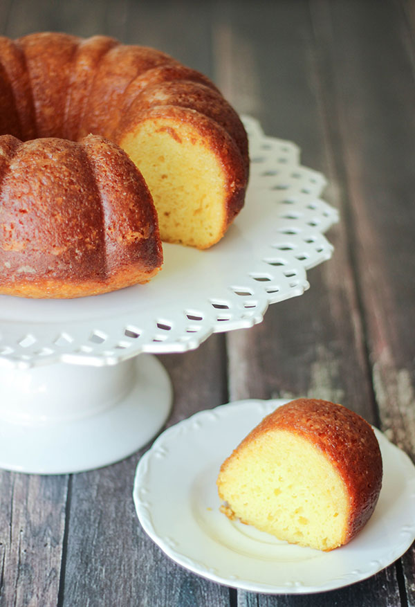 This bunt style coconut rum cake is made from yellow cake mix and styled on a white cake pedestal. 