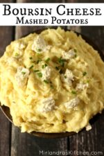 Big pottery bowl of yellow gold mashed potatoes with boursin cheese and chives on top.