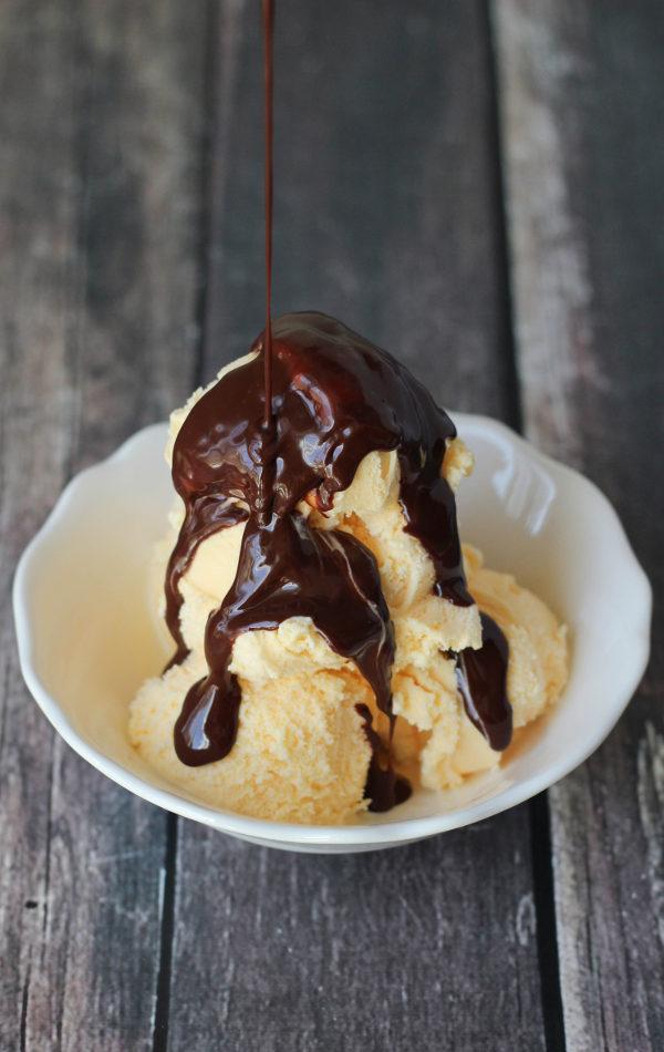 decadent hot fudge sauce is drizzled over vanilla ice cream in a white bowl.