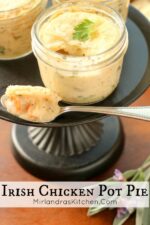 Three individual chicken pot pies baked in mason jars sit on a black stand. You can see the puff pastry crust and bites of carrots and a creamy sauce.