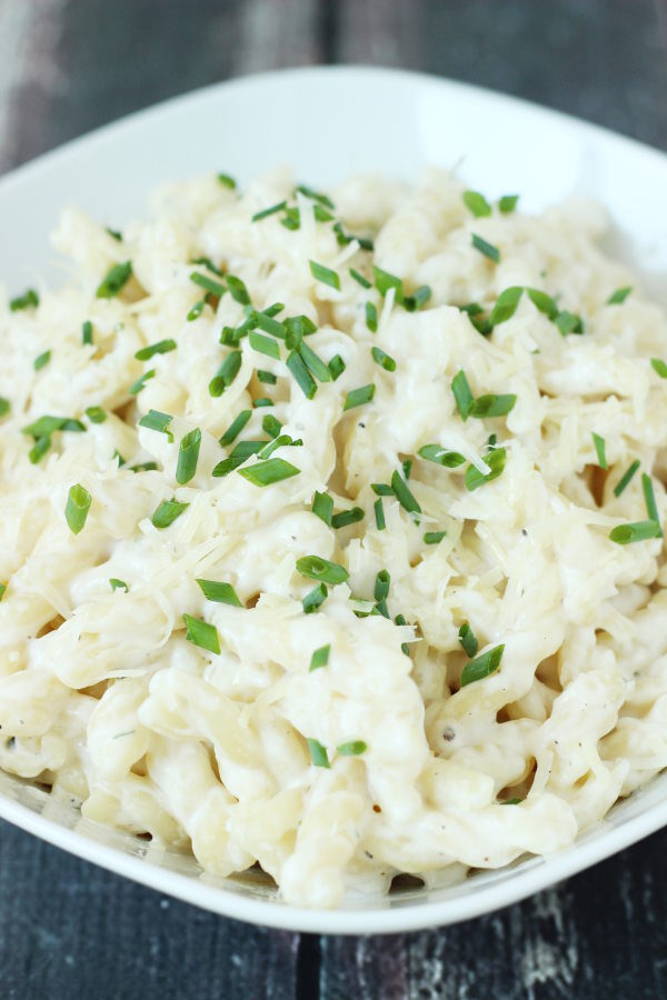 A large white bowl is full of creamy one pot pasta made with boursin cheese.  Minced chives garnish the pasta.