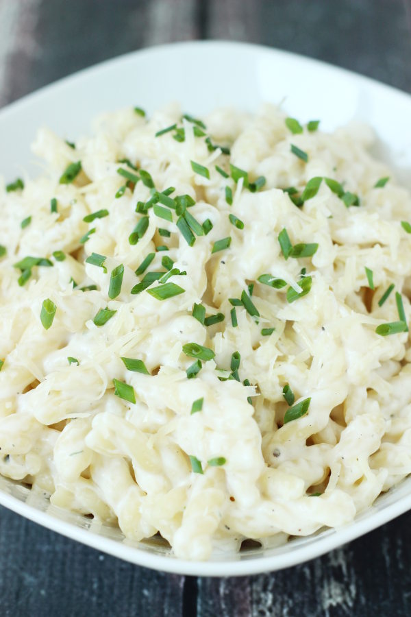 A large white bowl is full of creamy one pot pasta made with boursin cheese. Minced chives garnish the pasta.