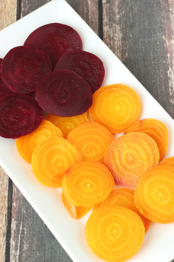 A white rectangular platter is filled with lovely sliced beets. The top of the platter holds slices of purple beets while the bottom holds slices of golden beets. These are soft from being cooked in the Instant pot.