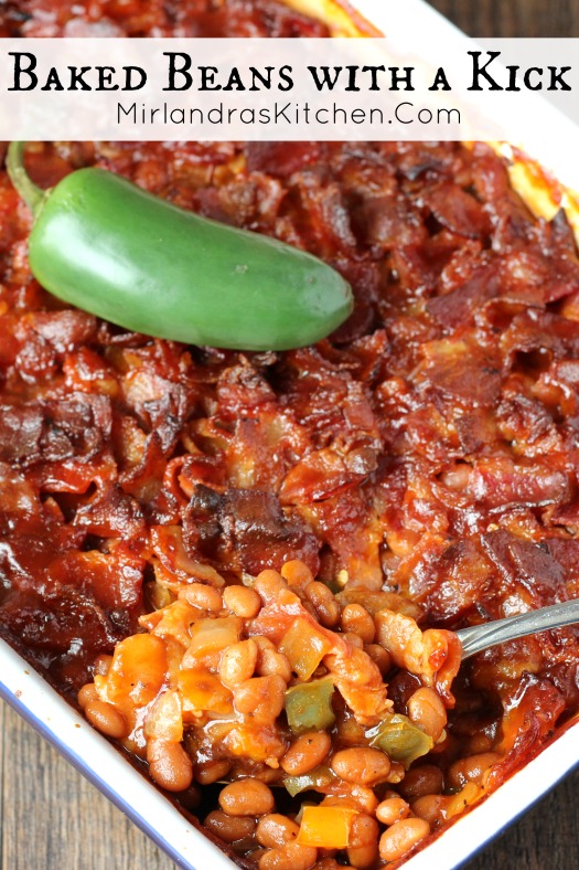 A casserole dish full of baked beans. The top is covered with chopped bacon and there is a jalapeno pepper on top for garnish.