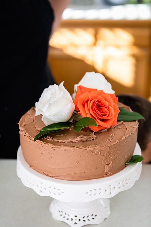 Black Magic Cake with decadent chocolate buttercream. This cake is decorated wtih fresh roses in white and orange.