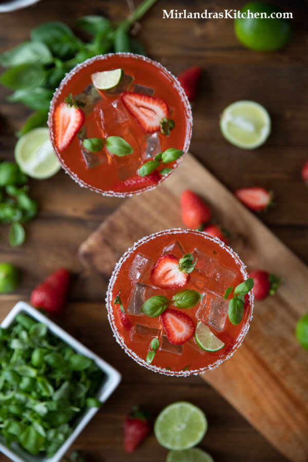 Overhead shot of strawberry margaritas on the rocks with basil.