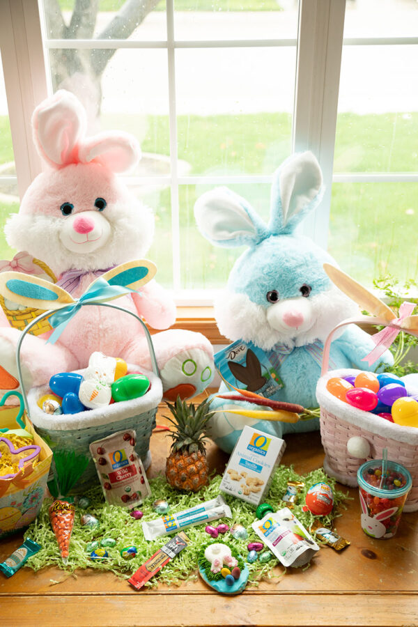 Easter baskets and gifts sit with two giant stuffed bunnies for toddler Easter fun.