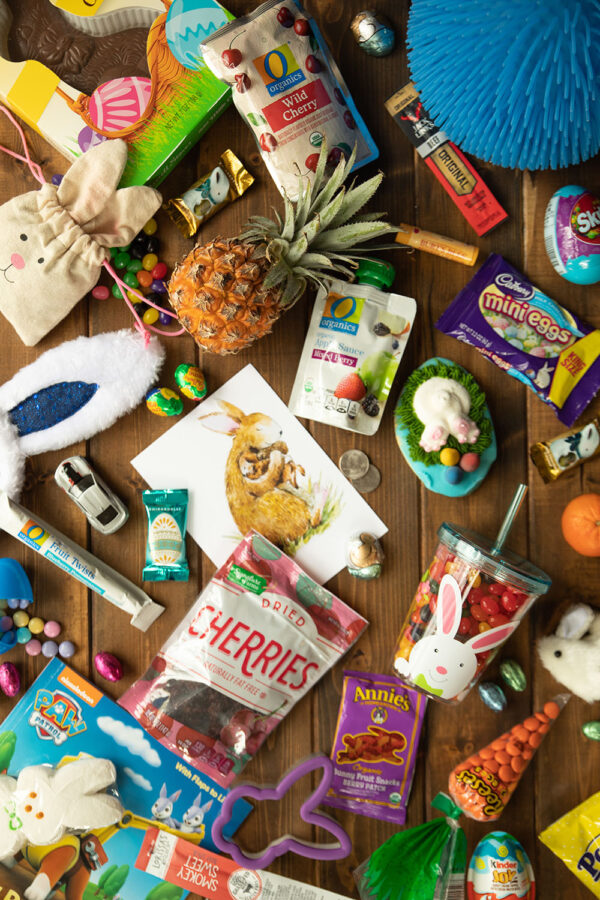 A variety of Easter Basket items for toddlers are arranged on a wooden table. 