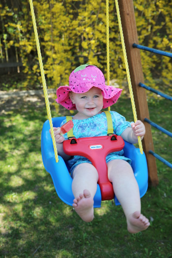 Ella in her swing eating a watermelon tree. 