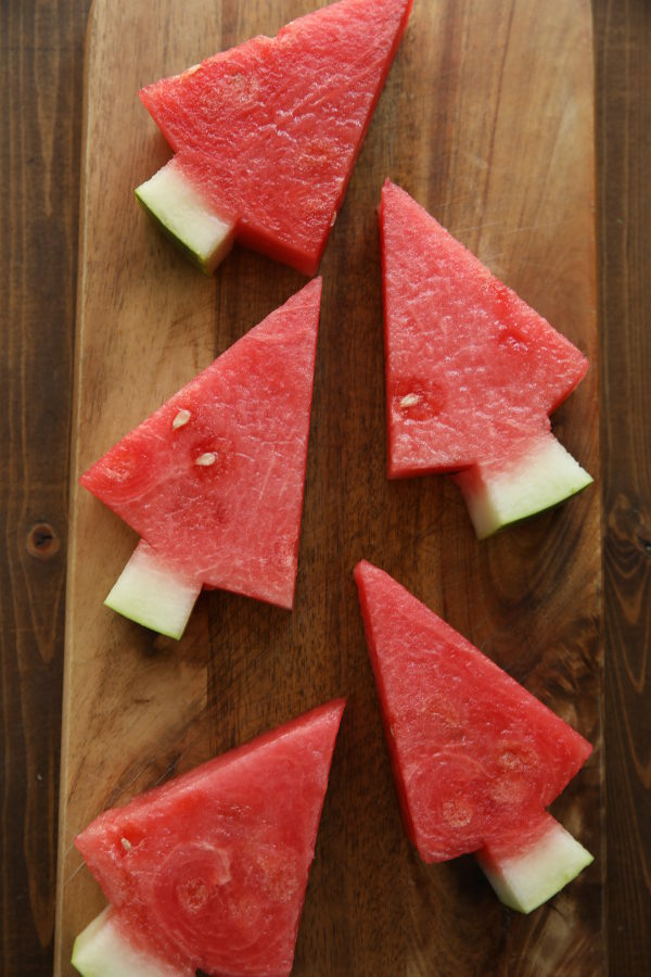 watermelon cut into tree shapes.  These watermelon trees are laid out on a cutting board ready for lunch. 