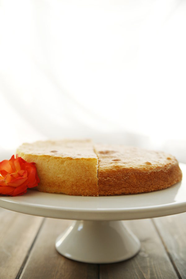 Two half cakes on a cake pedestal. The cake on the left rose flat and fluffy. The cake on the right is harder and has darker, more crusty edges. 