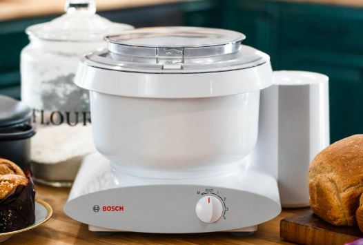 a bosch stand mixer with bottom drive function sits on the counter next to a loaf of bread