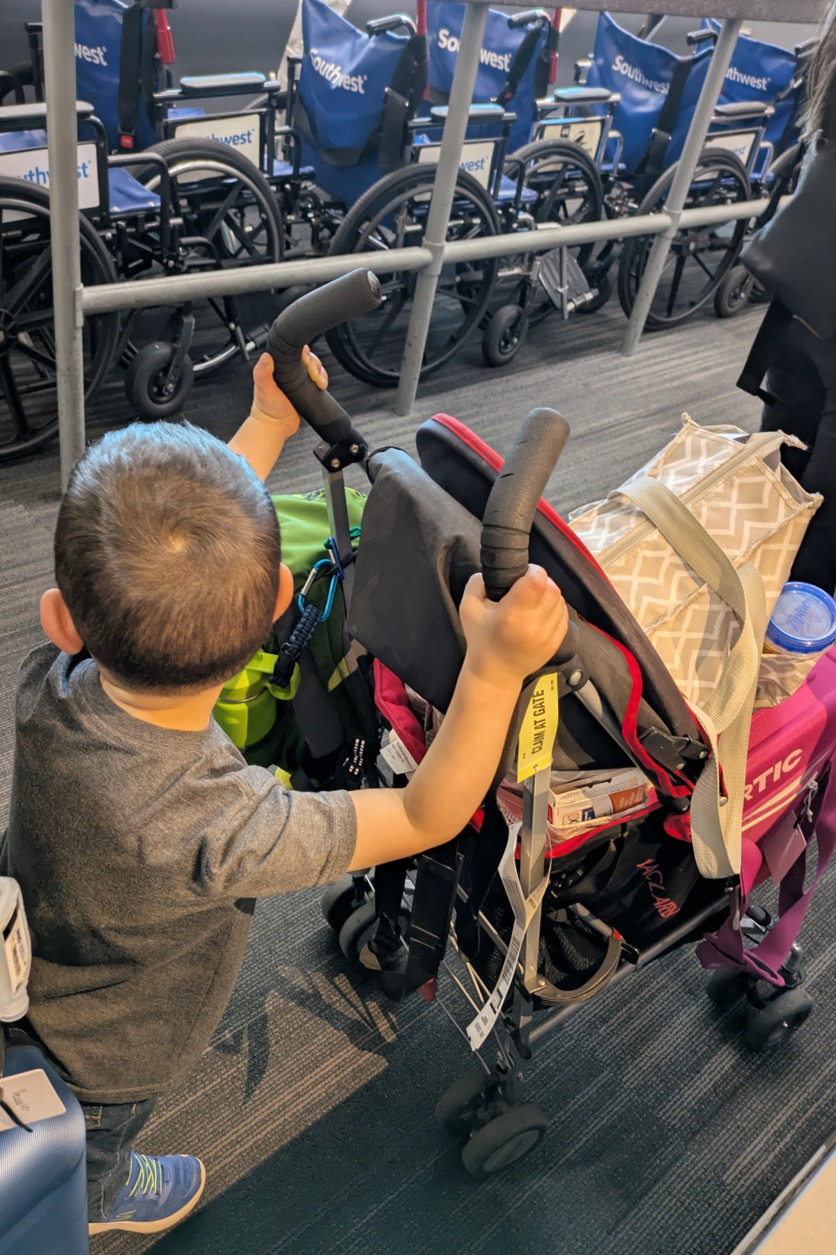 A toddler pushes our cooler through the airport in his stroller after going through TSA with the food.