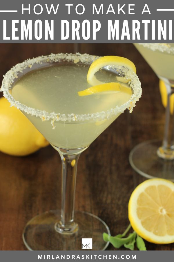 Pinterest image for how to make a lemon drop martini.  There is a dark wood table, a clear martini glass full of a light yellow lemon martini garnished with lemon sugar and a lemon twist.  The background has lemons and green sage leaves.