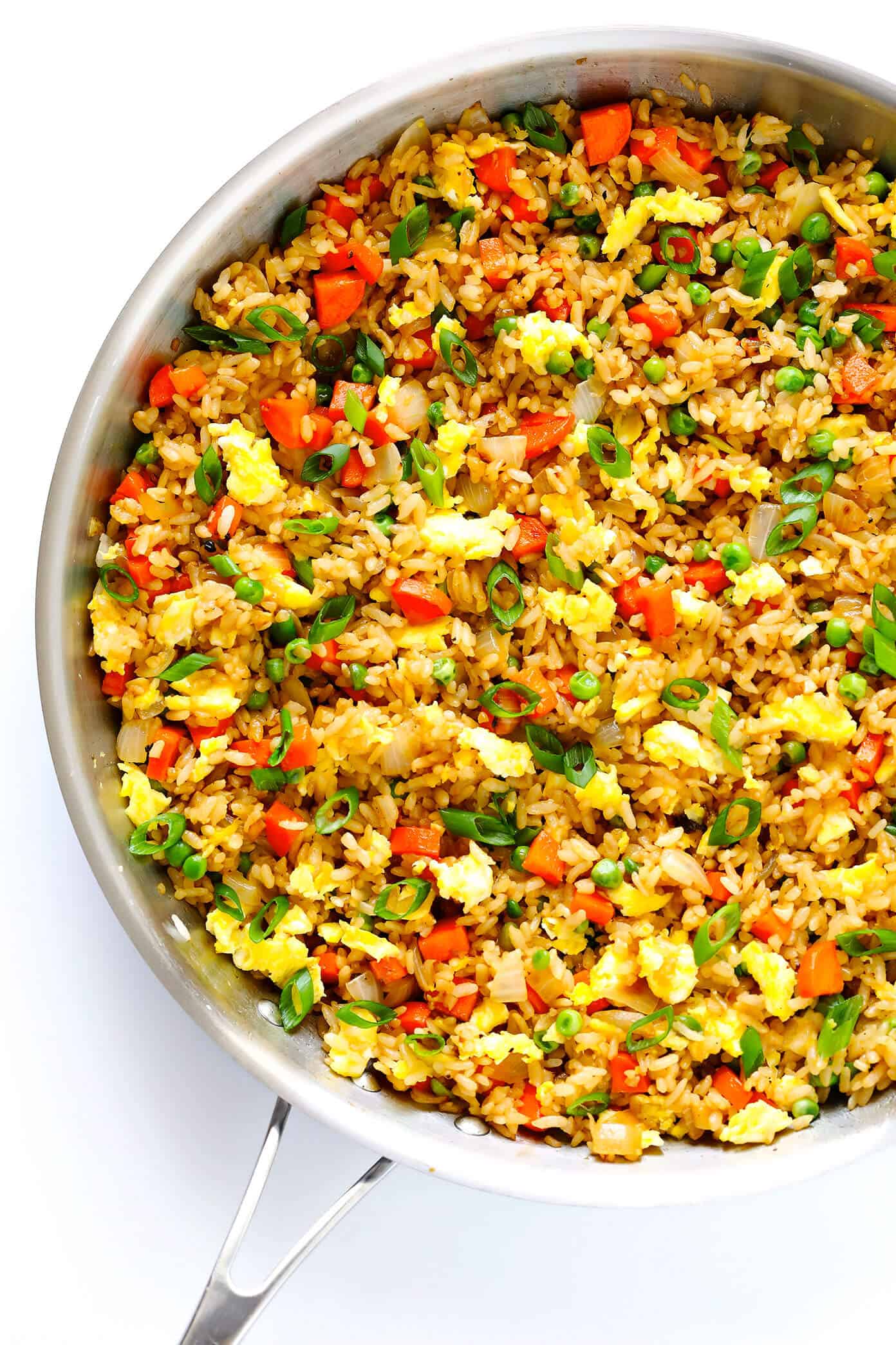 A large pan of fried rice garnished with green onions.