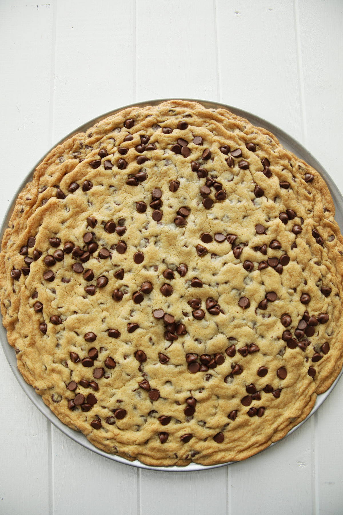 A fresh chocolate chip cookie cake decorated with a few extra chocolate chips on top. 