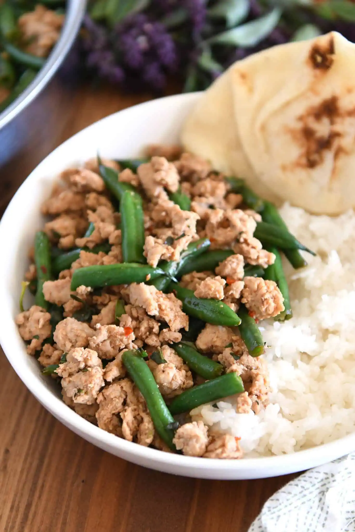 A rice bowl with green beans and turkey. You can see some flat bread at the back of the bowl.