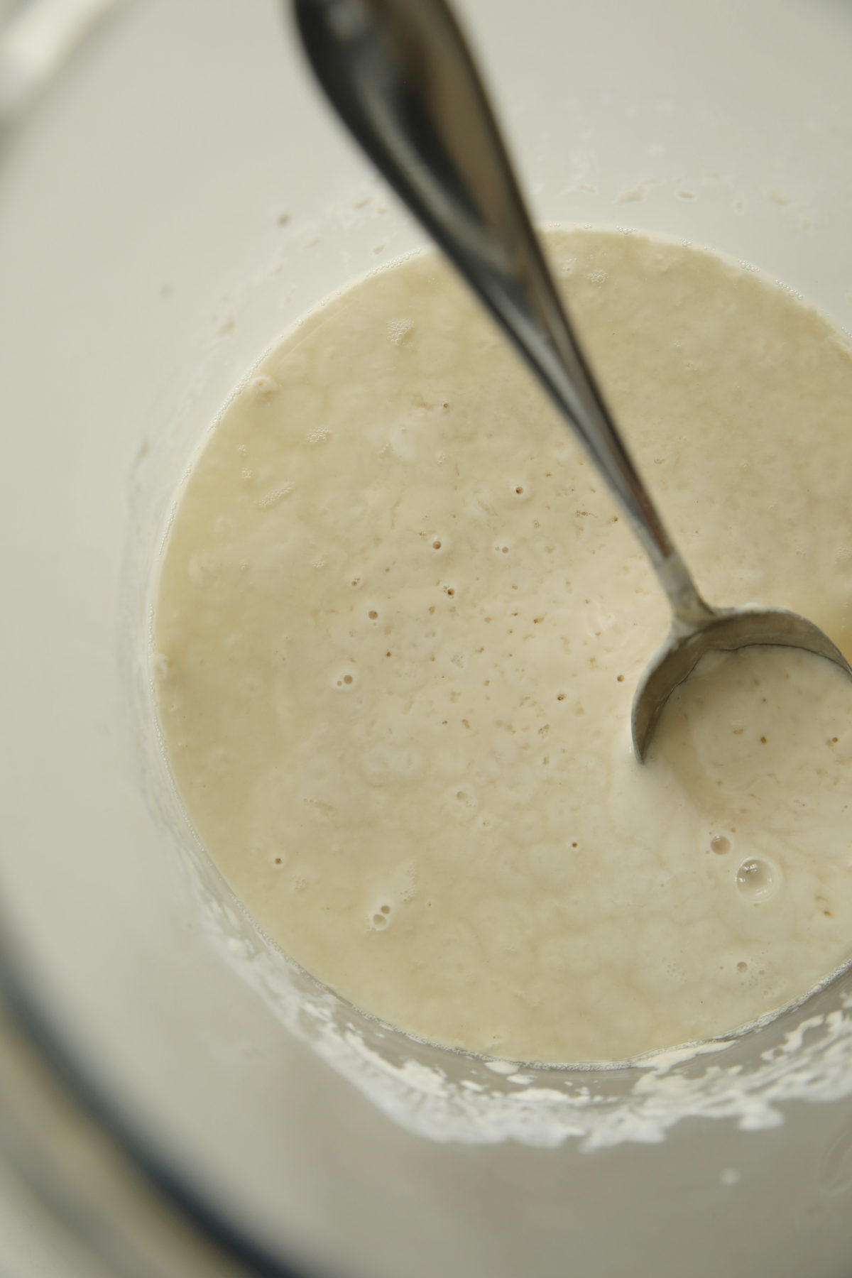 A large jar of sourdough starter that has not been fed for several days. You can see the hooch on top ready to be poured off.