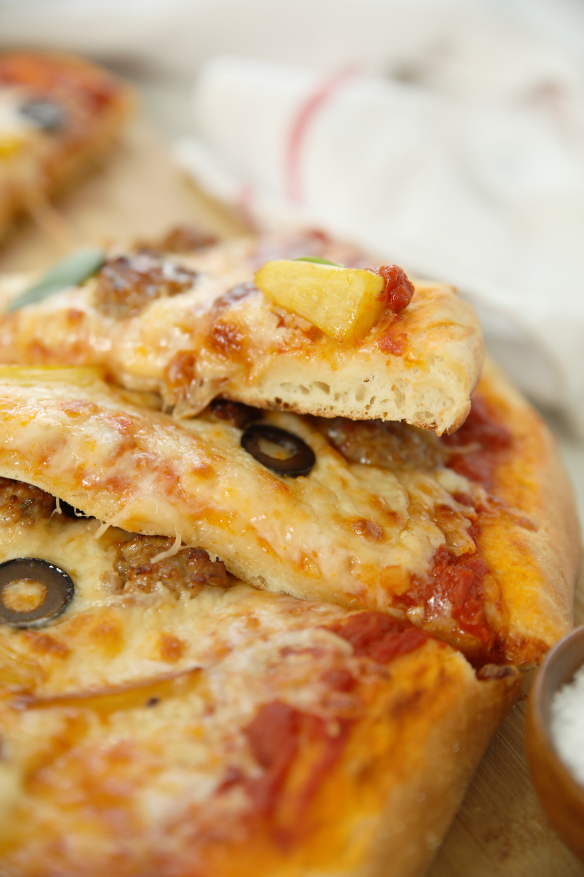 Slices of pizza made from sourdough discard pizza dough are stacked up so you can see the interior crumb.