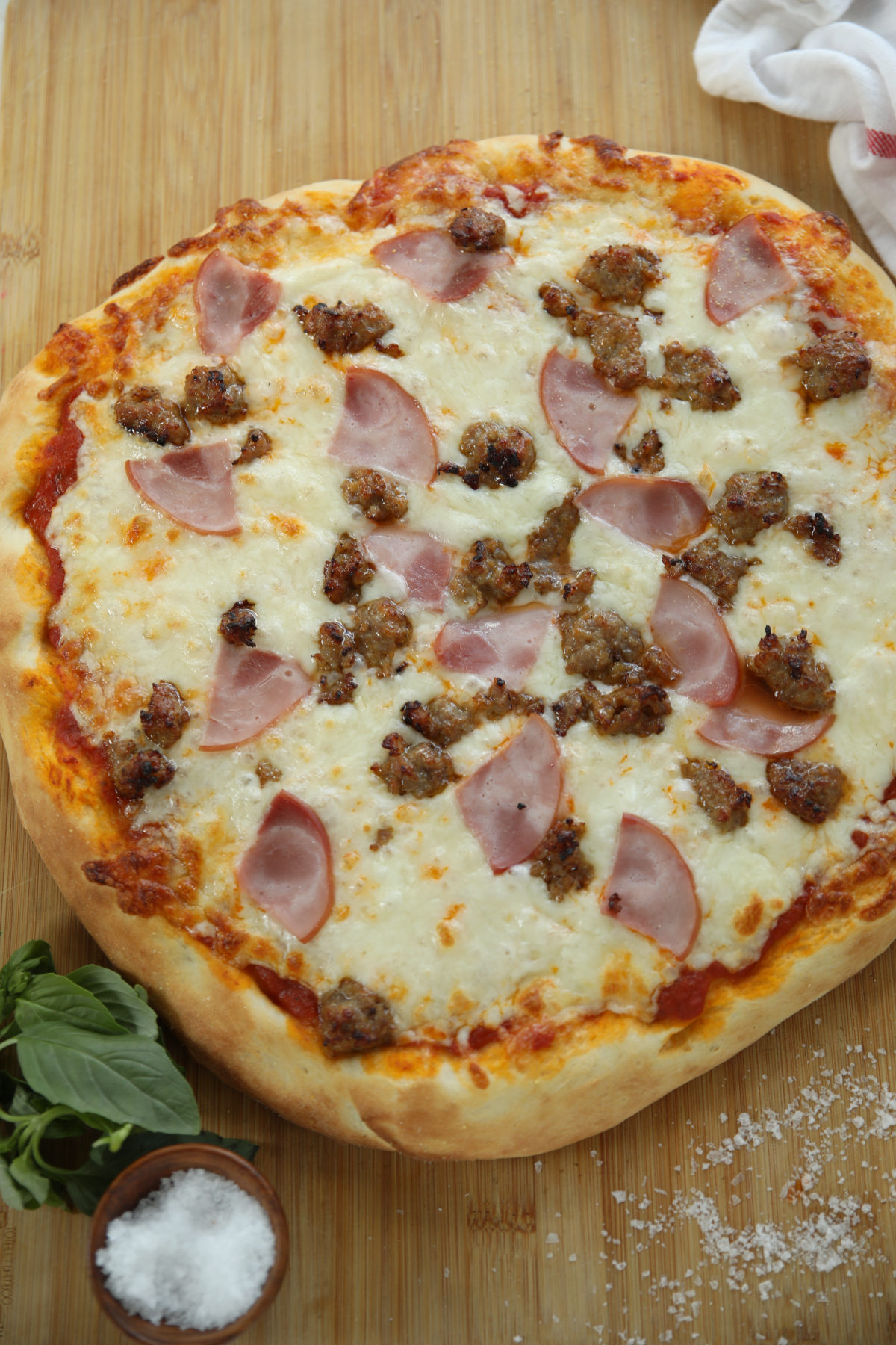 Sourdough discard pizza dough recipe baked into a big 16" pizza with sausage and Canadian bacon.