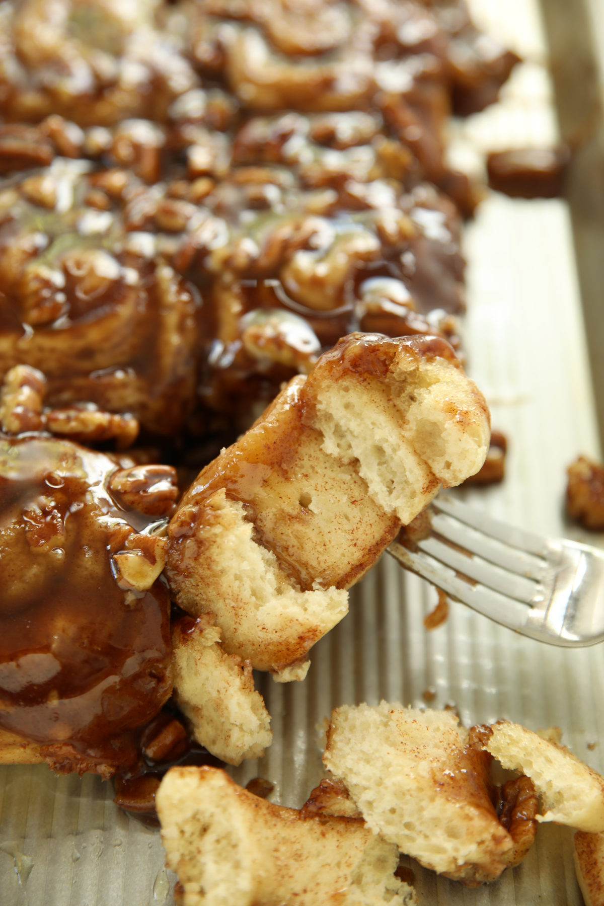 Soft and pillowy sourdough discard sticky bun pulled apart on a fork showing the fluffy interior layers