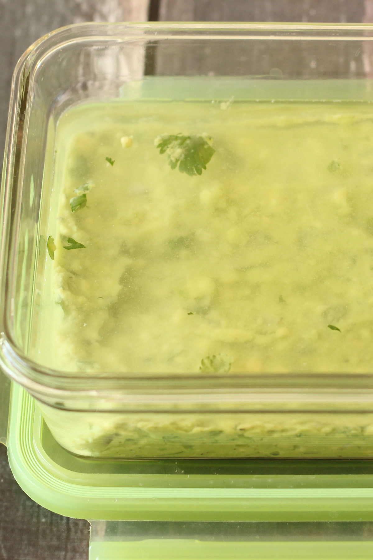 Guacamole stored in a glass container with a thin layer of water on top to prevent browning