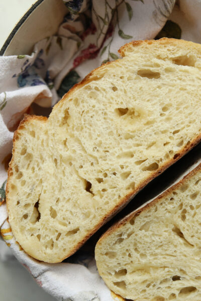 Sliced marzipan sourdough bread showing chunks of sweet marzipan throughout the golden crumb, cut loaf resting in a floral-lined basket